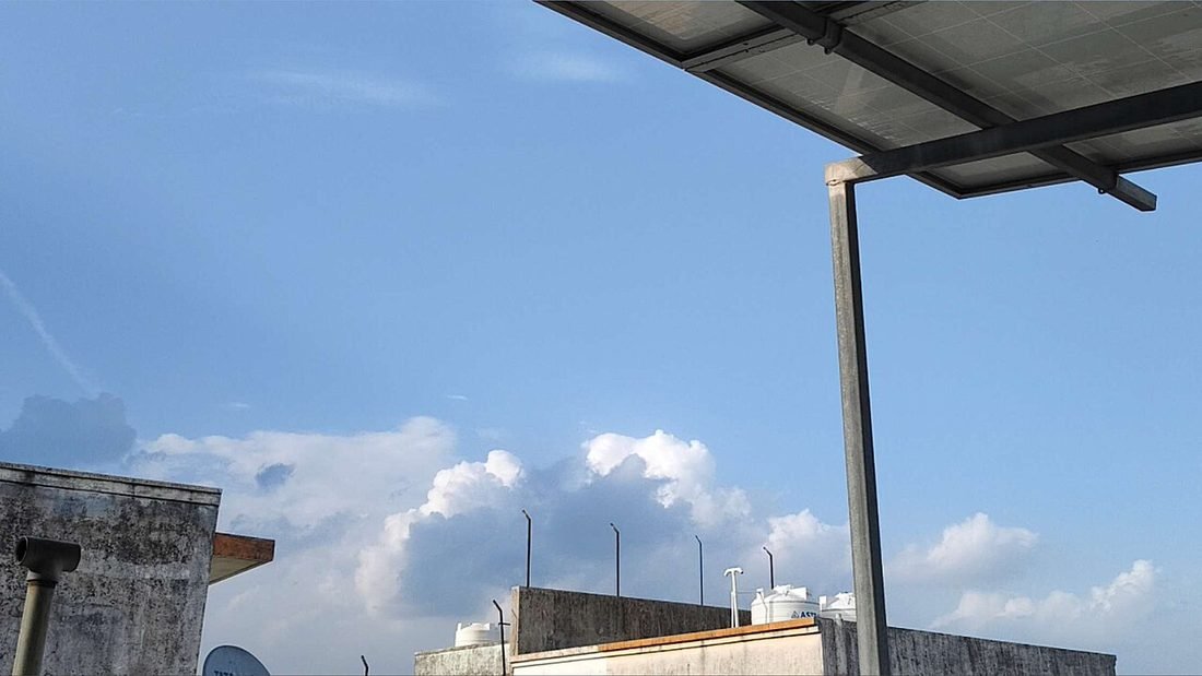 Solar panel canopy under a blue sky with clouds, showing the clear weather that makes the post-monsoon months a good time to install solar