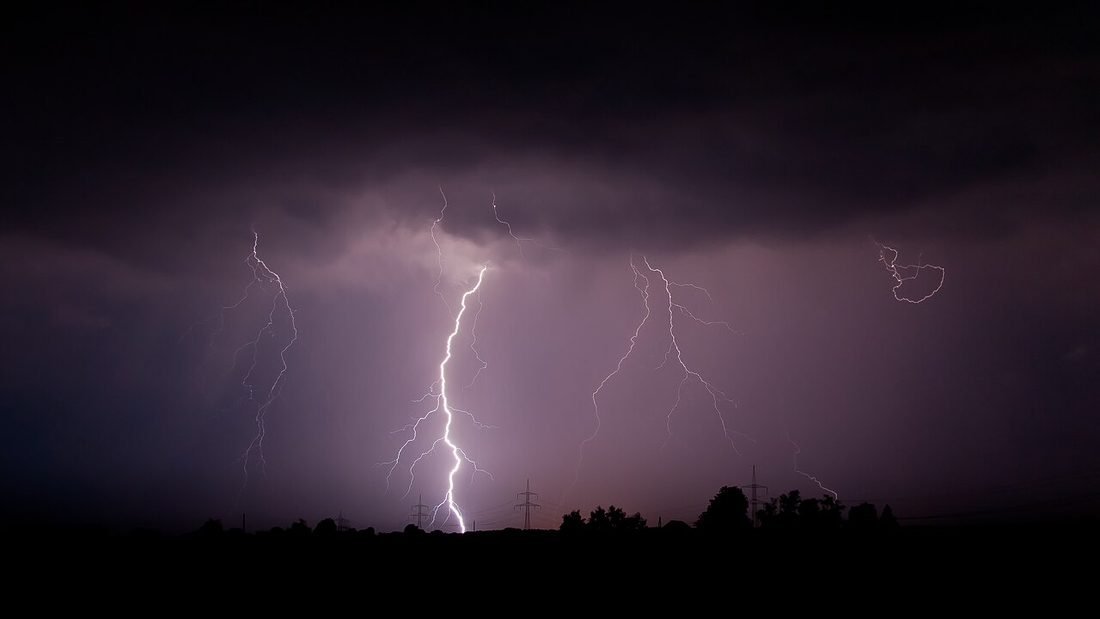 Lightning striking at night over open land, illustrating the lightning risk that rooftop solar systems in Chhattisgarh must be protected against