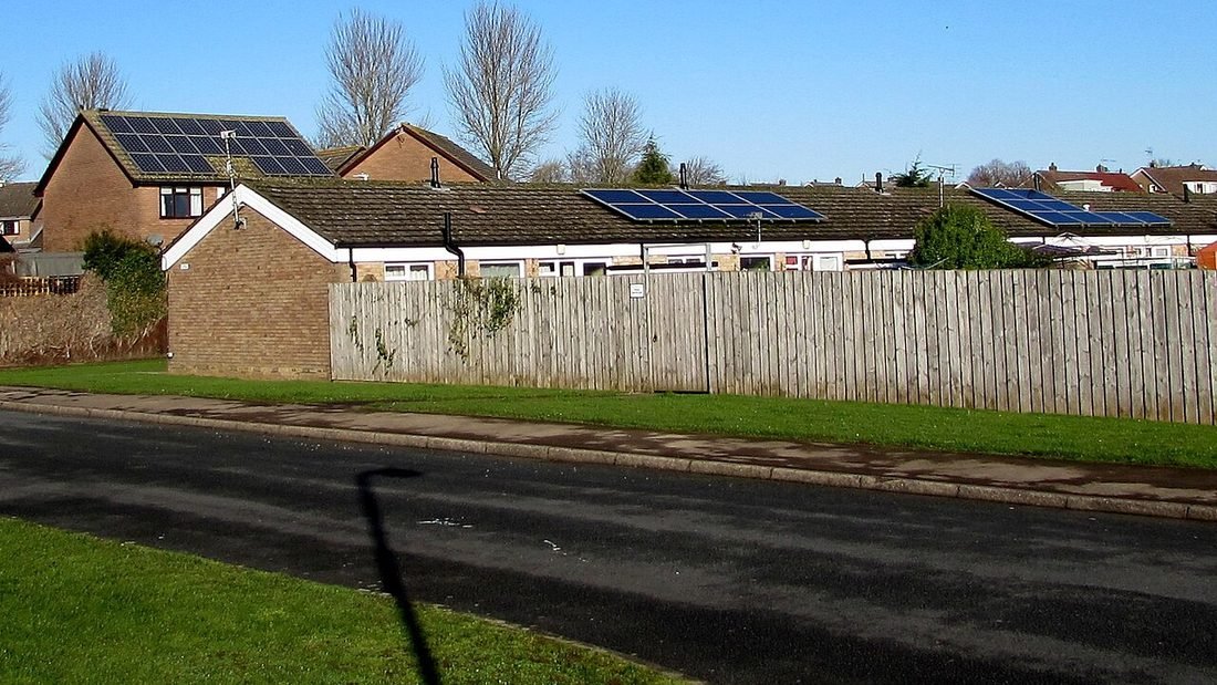 Residential rooftop solar panels on houses along a street, a typical net-metered home setup