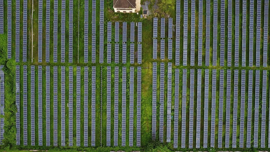 Aerial view of a large solar farm with rows of panels, representing solar generation that batteries can store