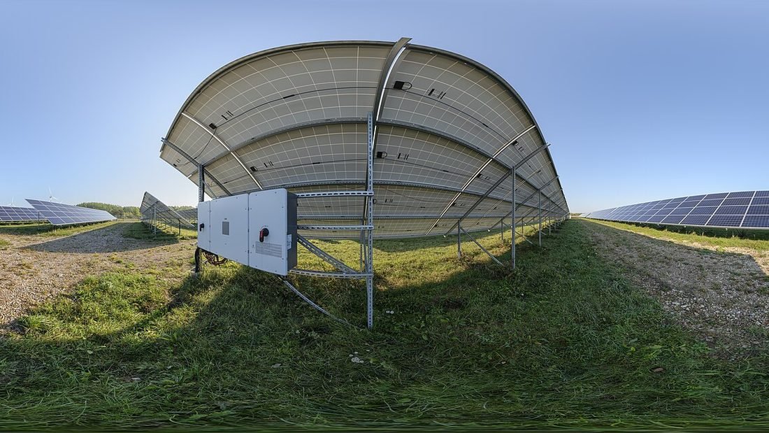 Ground-mounted solar array with inverter and mounting equipment, showing the inverter side of a solar system