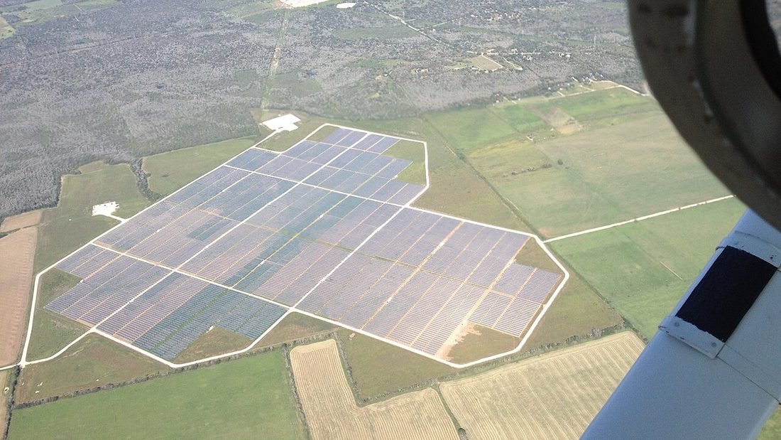 Aerial view of a solar plant laid out in rows facing the same direction on open land