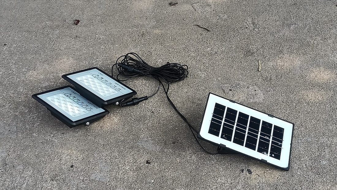 Small solar-powered LED floodlights with a separate panel on the ground, showing solar lighting components