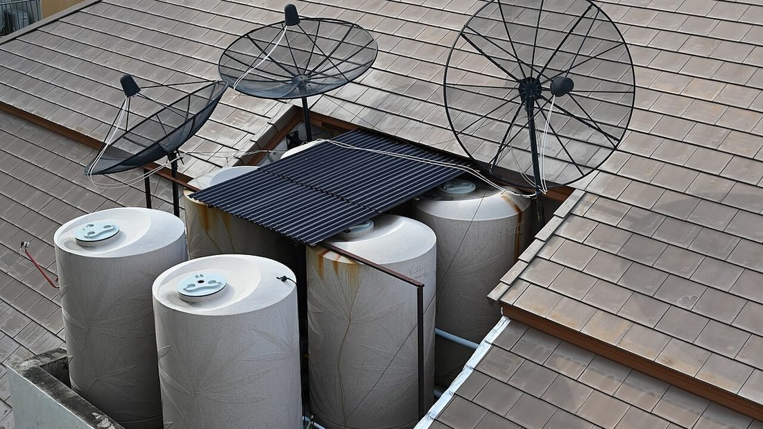 Rooftop with plastic water tanks and satellite dishes, typical obstructions that shade solar panels