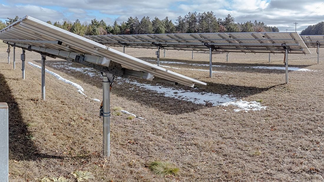 Ground-mounted solar panels on a two-axis tracker frame, showing the structure that must resist wind